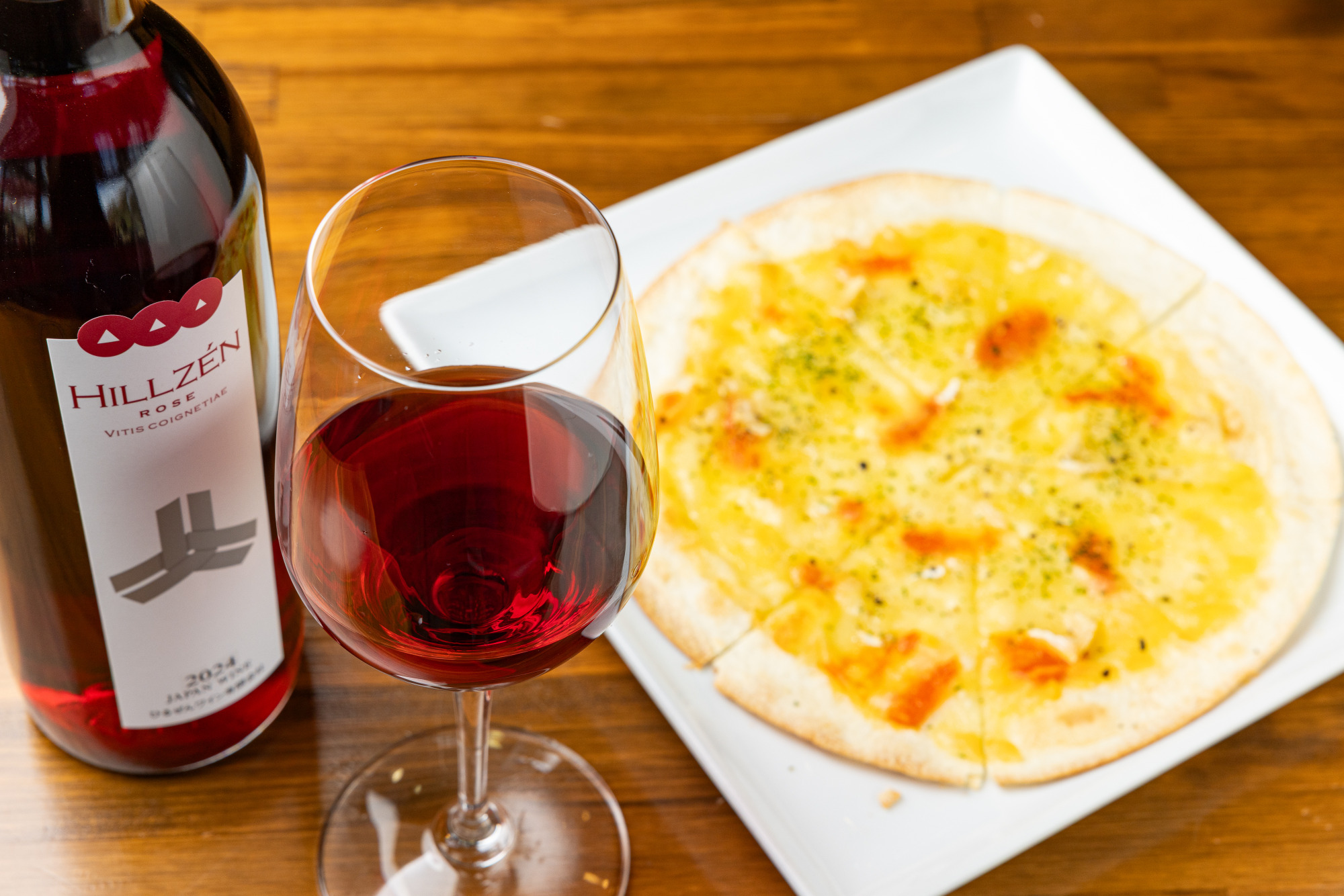 「山葡萄-ロゼ」グラス大850円とチェダーチーズとカマンベールチーズをのせた「ジャージーチーズピザ」900円 ※ピザの提供は11:00~15:30